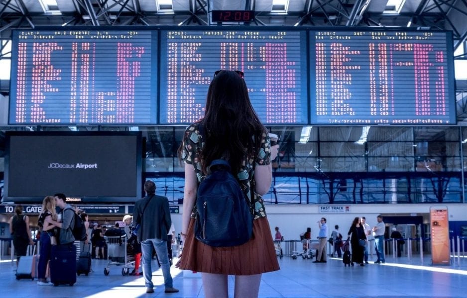 girl looking at billboard travelling alone - solo female travel europe