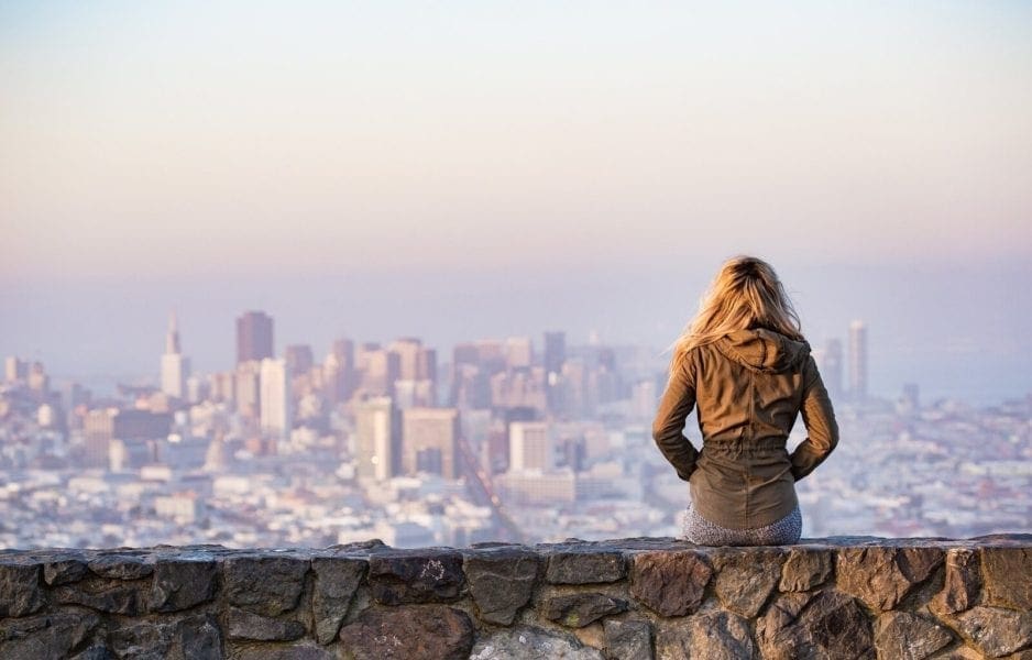 girl sitting on a wall overlooking the city - benefits of travelling solo